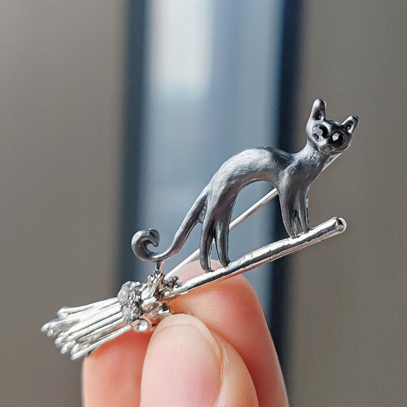 gold cat brooch with broom design